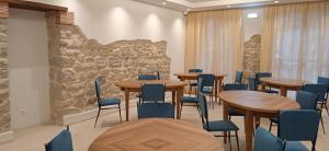 Habitación con mesas, sillas y pared de piedra. en Hotel Valle del Fiora, en Santa Fiora