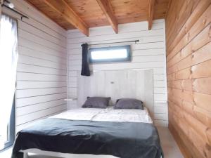 a bed in a white room with a window at Chalet cosy climatisé avec parking et Internet in Doué-la-Fontaine