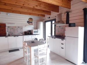 - une cuisine avec des appareils blancs, une table et des chaises dans l'établissement Chalet cosy climatisé avec parking et Internet, à Doué-la-Fontaine