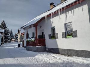 ein Haus mit Eiszapfen vom Dach im Schnee in der Unterkunft U Berňáků in Abertamy