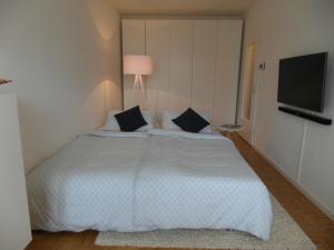 um quarto com uma grande cama branca com almofadas pretas em Cosy little apartment em Munique