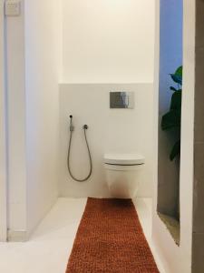 a bathroom with a toilet and a red rug at Saffron Robes Living in Hikkaduwa