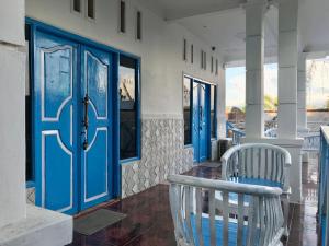 um alpendre com portas azuis e uma cadeira branca em The House Hostel em Gili Trawangan