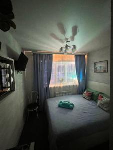 a small bedroom with a bed with a window at Sport Hotel Terra in Ustʼ-Kamenogorsk