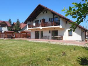 une grande maison blanche avec une pelouse devant elle dans l'établissement Casa Rudi & Ella, à Sălişte