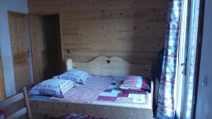 Bett in einem Holzzimmer mit Kissen darauf in der Unterkunft Votre appartement savoyard de 32m2 à proximité de la télécabine pour skier les 3 Vallées ! in Villarlurin