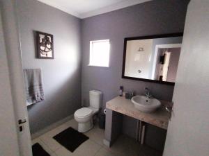ein Badezimmer mit einem WC, einem Waschbecken und einem Spiegel in der Unterkunft Protea Private Suite - Ramsgate Ramble Rest in Margate