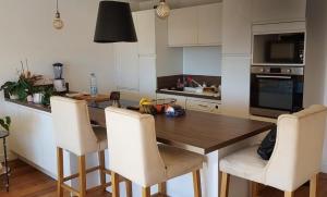 eine Küche mit einem Holztisch und weißen Stühlen in der Unterkunft chambre lit 2 personnes dans appartement du logeur in Mandelieu-la-Napoule