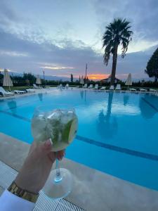 a person holding a drink in front of a pool at ANYA RESORT HOTEL in Pamukkale