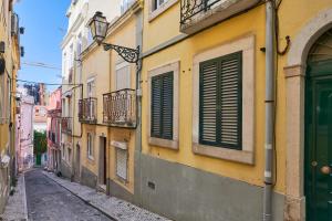 里斯本的住宿－Idyllic Lisbon Apartments With Amazing Courtyard, By TimeCooler，黄色建筑上一条带绿门的小巷