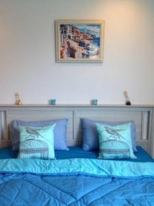 1 cama con almohadas azules y una foto en la pared en Chelona Hua Hin, en Khao Tao