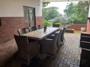 un tavolo in legno e sedie su un patio in mattoni di 10 st Johns - House a Port Shepstone