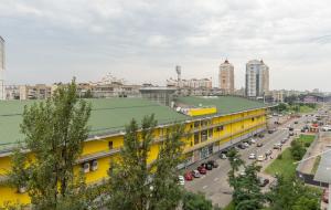 un edificio amarillo con techo verde en una ciudad en Світла, комфортна квартира біля метро Мінська, en Kiev
