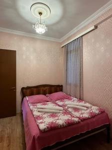 a bedroom with a bed with pink sheets and a chandelier at Sun Apartment in Tbilisi City