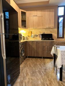 a kitchen with wooden cabinets and a sink and a dishwasher at Sun Apartment in Tbilisi City
