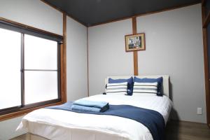 Tofukuji Saku Inn（东福寺咲く宿） في كيوتو: غرفة نوم مع سرير ووسائد زرقاء وبيضاء