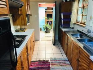 a kitchen with wooden cabinets and a sink and a doorway at LRN Brackenfell Homestay in Cape Town