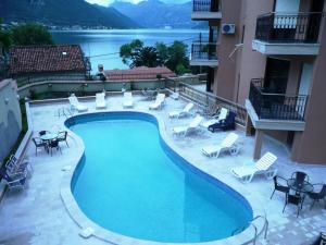une grande piscine avec des chaises longues et un bâtiment dans l'établissement Apartments Coral, à Kotor