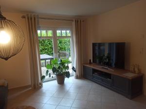 sala de estar con TV de pantalla plana y planta en Schöne 77qm Wohnung in gehobener Lage direkt am Wald, en Rodenbach