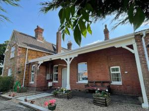 ein Backsteinhaus mit einer Bank davor in der Unterkunft The Old Station, Station House, Snettisham Norfolk in Snettisham