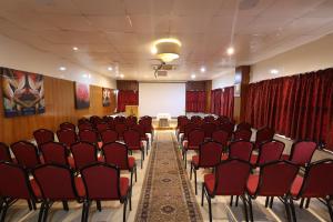 sala konferencyjna z czerwonymi krzesłami i białym ekranem w obiekcie Akash Inn w mieście Shivamogga