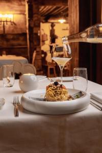 a plate of pasta on a table with a glass of wine at Camana Veglia in Livigno