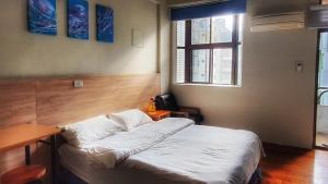 1 dormitorio con cama, escritorio y ventana en 翼想旅宿-2022營運車站前花蓮民宿 en Hualien