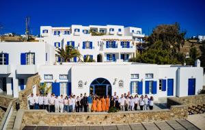 a group of people standing in front of a white building at San Antonio Summerland in Mikonos