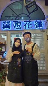 two people wearing masks standing in front of a store at 翼想旅宿-2022營運車站前花蓮民宿 in Hualien City