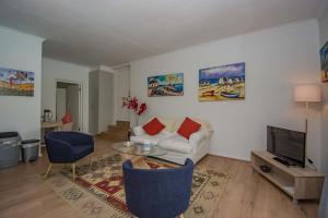 a living room with a white couch and a tv at Garden- Pool flat with Solar Electricity in Somerset West