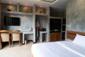 a bedroom with a bed and a desk and a tv at Anodard Phuket, Nai Yang Beach in Thalang