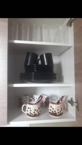 a cupboard with plates and cups and dishes on them at Apartman 053 in Doboj