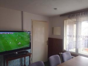 una sala de estar con TV con un partido de fútbol. en Small house in Celje en Celje