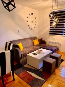 un soggiorno con divano e orologio sul muro di Lux 05 a Lukavica