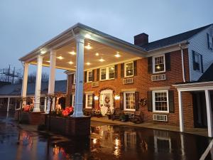 シーコンクにあるColonial Inn Seekonkの屋根付きの玄関がある大きなレンガ造りの家