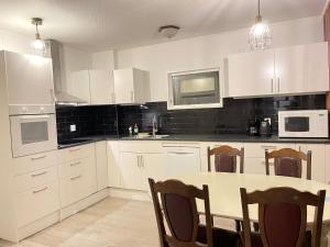 a kitchen with white cabinets and a table with chairs at Villa med 4 sovrum in Gothenburg