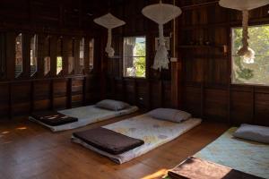 3 camas num quarto com pisos e janelas em madeira em Art House at Chiangdao - StarHouse em Chiang Dao