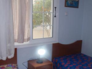 um quarto com uma janela e um candeeiro sobre uma mesa em Traditional city house em Kalymnos