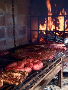 una griglia con un mucchio di carne e un fuoco di Casa de campo - retiro con encanto en las sierras a Minas