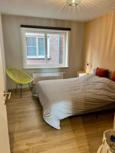 ein Schlafzimmer mit einem großen Bett und einem gelben Stuhl in der Unterkunft Appartement entièrement rénové à Blankenberge in Blankenberge