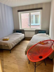 Zimmer mit 2 Betten und einem roten Stuhl in der Unterkunft Appartement entièrement rénové à Blankenberge in Blankenberge