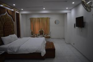 a bedroom with a bed and a chair and a television at Relax Inn in Lahore