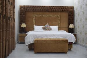拉合爾的住宿－Relax Inn，一间卧室配有一张大床和大型木制床头板