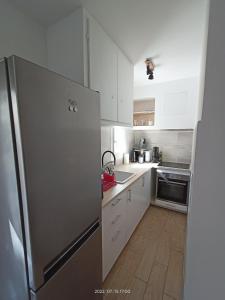 een keuken met witte kasten en een roestvrijstalen koelkast bij T2 rénové en RDC avec cour, Intra Muros Avignon in Avignon