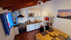 a kitchen with white cabinets and a table with a dining table at Casa Marcos in La Gomera with relaxing terrace in Agulo