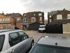 two cars parked in a parking lot with houses at 287 Green Lanes in London