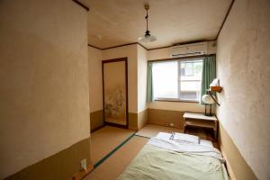 Guesthouse Bon في كيوتو: غرفة صغيرة بها سرير ونافذة