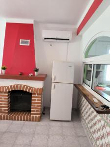 a kitchen with a white refrigerator and a fireplace at Apartamentos Campos 0 in Porto Covo