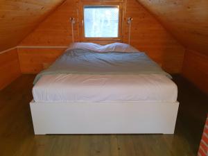ARIA في Sviščaki: سرير أبيض في غرفة خشبية مع نافذة