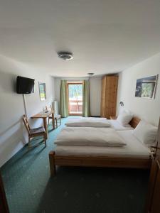 a bedroom with two beds and a table and a window at Arlbergsun in Pettneu am Arlberg